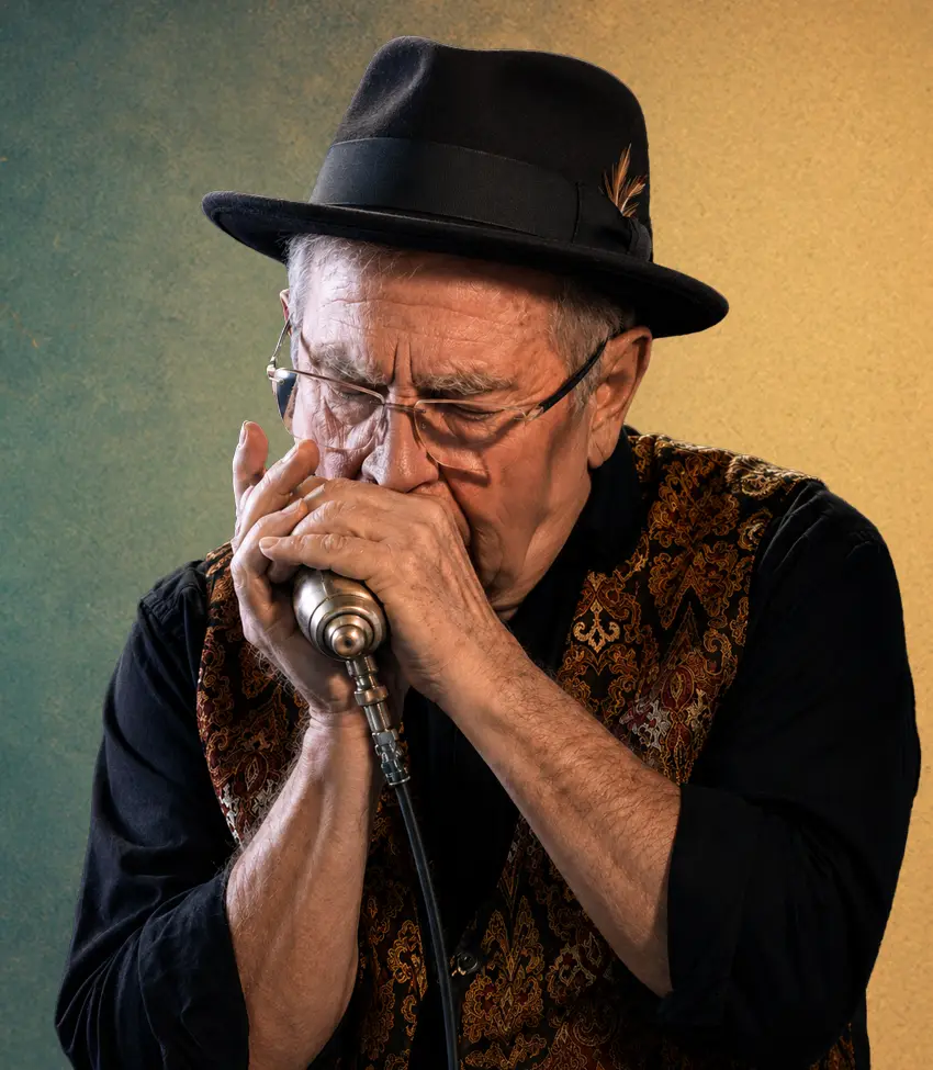Ian Wilks blowing a harmonica playing electrified Blues